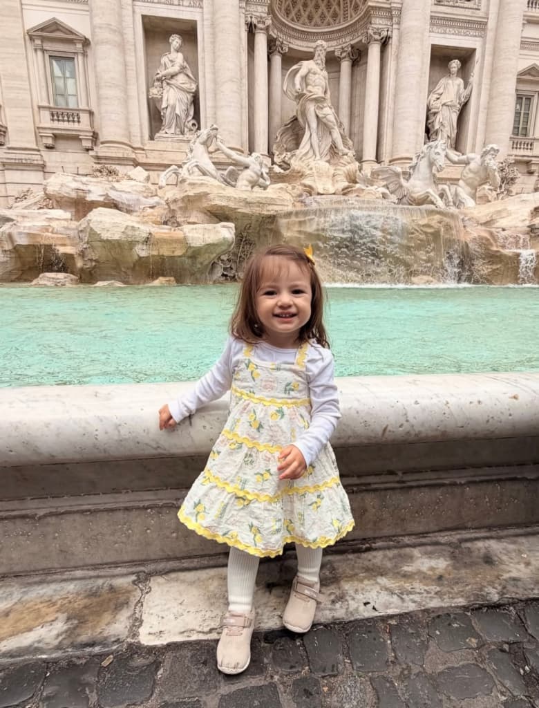 My daughter smiling in front of a fountain on a family trip