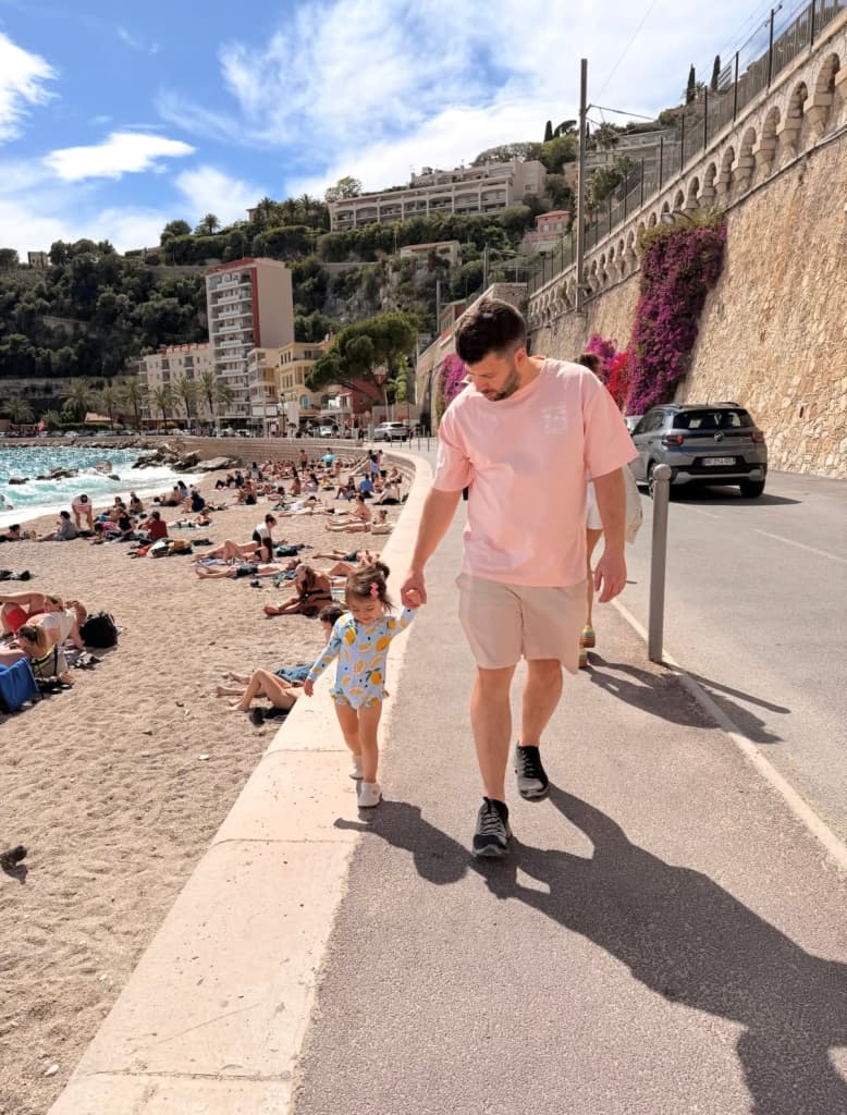 A father and daughter holding hands on a seaside walk